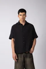 Camisa negra de lino con cuello clásico, manga corta y cierre frontal con botones.