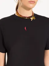 Remera blanca de jersey pesado con escote redondo, mangas cortas y bordado de un ají rojo en el frente.