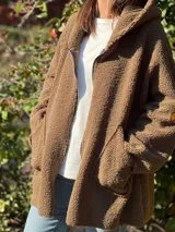 Campera color ocre con capucha y cierre frontal asimétrico.