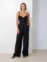 Pantalón palazzo de tiro alto color violeta, de satén. Tiene pretina delantera con pasadores, botón y cierre, pretina trasera elastizada y bolsillos verticales delanteros.