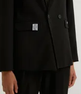 Blazer negro de poliéster y viscosa, de corte alargado, con cuello solapa, manga larga, doble botón frontal y bolsillos con solapa.