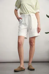 Short de vestir color beige claro, tiro alto, con pliegues frontales y lazo para ajustar la cintura.