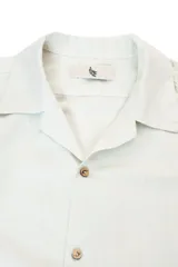 Camisa de manga corta color crema, con cuello camp y calce relajado. Confeccionada en mezcla de algodón y lino, con botones de coco con logo y parche característico de Polonio.