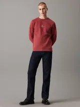 Buzo de felpa color ladrillo con cuello redondo, puños y bajo acanalados. Presenta un logo bordado de Calvin Klein Jeans en el pecho.