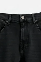 Pantalón de jean azul oscuro, corte slim fit, tiro medio, cinco bolsillos, tejido elástico y efecto lavado.