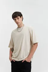 Remera de manga corta color beige, corte oversize y cuello redondo.