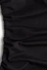 Vestido midi negro de punto elástico con escote asimétrico, manga corta con detalle girado, frunces en un hombro y en un lateral para crear un leve efecto drapeado.