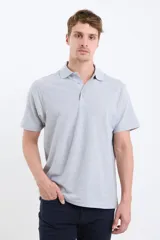 Remera polo de hombre color verde claro, manga corta, con cuello clásico y tapeta de dos botones. Corte recto.
