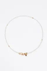 Collar de doble cadena que combina una hilera de cristales facetados en diversos colores (rosa, azul, amarillo, naranja y verde) con una cadena fina plateada adornada con pequeños dijes en forma de corazón. Cuenta con un cierre de mosquetón y un detalle circular con logo.