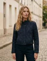 Campera de mujer color azul marino, con textura capitoneada de efecto burbuja o nido de abeja. Presenta cuello alto con cierre frontal y corte recto y corto.