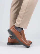 Zapato slip-on de cuero color marrón con suela negra y elástico lateral.