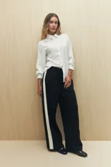 Pantalón de jogging color crema con cintura elástica, cordón ajustable y franja lateral negra.