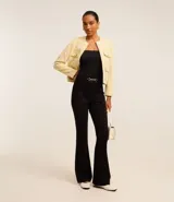 Pantalón flare negro de punto roma con detalle metálico en la cintura y cierre delantero.