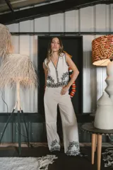 Pantalón de vestir color beige, de corte palazzo, con bordado de flores negras en el ruedo.