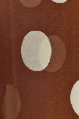 Vestido midi de tejido de punto color marrón, sin mangas y con cuello redondo. Presenta un estampado de lunares grandes en color crema/blanco roto.