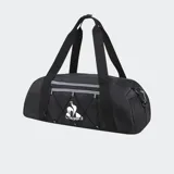 Bolso deportivo tipo duffle bag, color negro, con logo de Le Coq Sportif en blanco en el frente. Presenta un compartimento frontal con cordón elástico y tanca regulador con detalles reflectivos, y bolsillos laterales de malla.