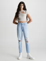 Jeans celeste claro de corte mom, con roturas en las rodillas, tiro alto, cinco bolsillos y cierre con botón y cremallera.