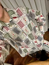 Camisa blanca con estampado de naipes en tonos rojo, verde, negro y beige.