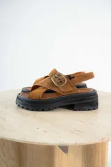 Sandalias bajas color marrón de cuero gamuzado, con tiras cruzadas y hebilla metálica.