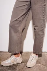 Jean de mujer color marrón topo, tiro medio, con corte barrel y puño doblado. Presenta costuras decorativas en la zona de las rodillas.