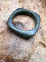 Pulsera rígida de forma cuadrada con bordes redondeados, color lila.
