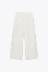 Pantalón blanco de lino, de corte ancho, tiro medio, con trabillas y cintura elástica ajustable con cordones.