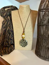 Collar con cordón marrón, cuentas de madera y dije circular con estampado de leopardo.