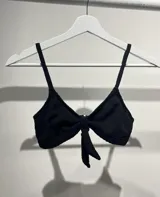 Conjunto de bikini negro con corpiño triangular con nudo central y tirantes finos.