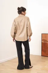 Camisa beige de efecto piel con cuello clásico, mangas largas abullonadas y cierre frontal con botones a tono.
