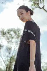 Vestido corto tejido en lurex negro con cuello redondo y mangas cortas.