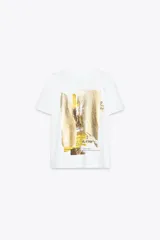 Camiseta blanca de manga corta y cuello redondo con estampado metalizado en el frente.