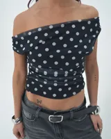Top negro con lunares blancos, de escote asimétrico y corte ajustado.