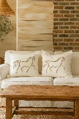 Almohadón cuadrado de lino color crema con bordado de hilo natural que representa un caballo. Tiene cierre invisible y relleno de alta densidad. Diseño artesanal.