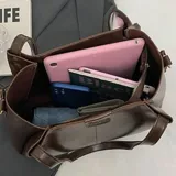 Cartera tote de cuero color marrón oscuro, con doble asa de hombro, cierre superior y bolsillo interno.