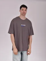 Remera gris topo de corte oversize con cuello redondo y estampado con texto en el pecho.