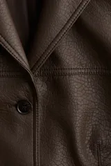 Blazer marrón de cuero sintético con solapas de muesca, cierre con tres botones, bolsillos delanteros con solapa y forro de sarga.
