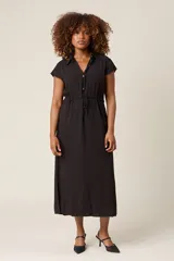 Vestido camisero negro con cuello, botones frontales y lazo ajustable en la cintura.