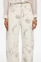 Pantalón denim blanco con estampado de motivos vegetales en gris, corte barrel, tiro medio, largo tobillero, con cierre frontal de botón denim, cinco bolsillos y costuras irregulares en los laterales.
