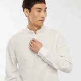 Camisa blanca de manga larga con cuello mao y textura gofrada.