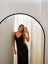 Vestido largo negro de seda, con escote en V adornado con encaje delicado y tirantes finos.