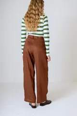 Pantalón negro de corte ancho y tiro alto, con pinzas en la cintura y bolsillos laterales.