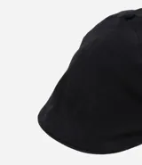 Boina color beige confeccionada en sarga, con una pequeña asa en la parte superior y cierre de elástico.