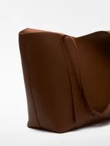 Bolso tipo shopper grande color marrón con textura granulada. Tiene un compartimento principal con cierre magnético y un bolso interior extraíble con cierre de cremallera. El asa de hombro tiene una hombrera y el logo está grabado.