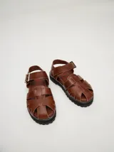 Sandalias de cuero color marrón con tiras entrecruzadas y hebilla lateral. Suela de goma con plataforma de 3cm.