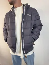 Campera inflada color ocre con capucha, cierre frontal con cremallera y logo de la marca bordado en el pecho.