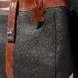 Bolso tipo tote de cuero color marrón con detalles en negro. Tiene doble asa de hombro y correa extraíble regulable. Incluye cierre principal y bolsillo interior.