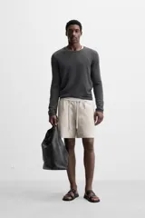 Bermuda regular fit negra confeccionada en tejido de lino. Cintura elástica ajustable con cordón y pliegues frontales. Bolsillos frontales y detalle de bolsillos traseros de plastrón.