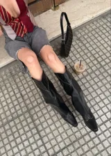 Botas texanas negras de caña alta con detalle de tachas doradas.