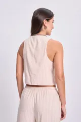 Chaleco corto color crudo con rayas verticales finas, escote en V y cierre frontal con lazos.