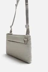 Bandolera negra fabricada en tejido técnico con correa ajustable. Tiene un compartimento principal con cierre de cremallera, un bolsillo interior con cremallera y un bolsillo frontal con cremallera y detalle de arnés.